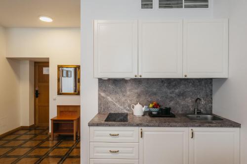 una cocina con armarios blancos y fregadero en CATHEDRAL Self-Service Aparthotel, en Vilna