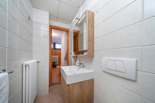 La salle de bains est pourvue d'un lavabo blanc et d'un miroir. dans l'établissement Le Coccinelle, à Tarvisio
