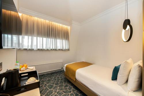 a hotel room with a bed and a television at Queens Park Premier London Hyde Park in London