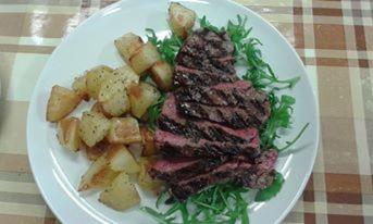 a plate of meat and potatoes on a table at Agriturismo Al Gelso in Risano