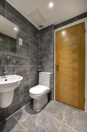a bathroom with a toilet and a sink and a wooden door at Queens Park Premier London Hyde Park in London