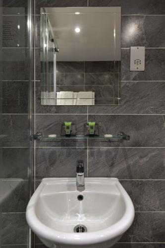 a white sink in a bathroom with a mirror at Queens Park Premier London Hyde Park in London