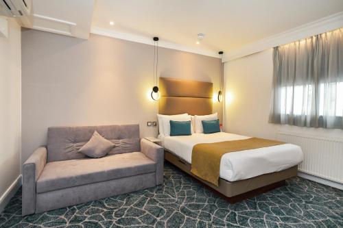 een hotelkamer met een bed en een bank bij Queens Park Premier London Hyde Park in Londen