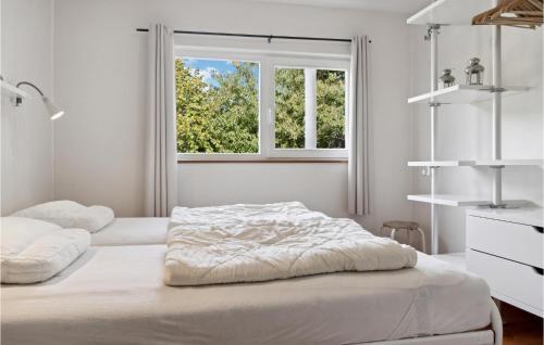 Amazing Home In Askeby With Sauna في Askeby: سريرين في غرفة بيضاء مع نافذة