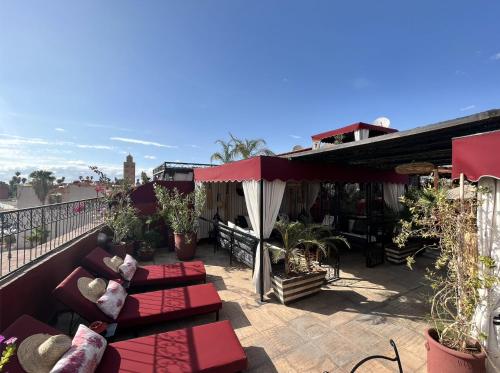 a patio with red couches and plants on a balcony at Dar L'hna in Marrakech