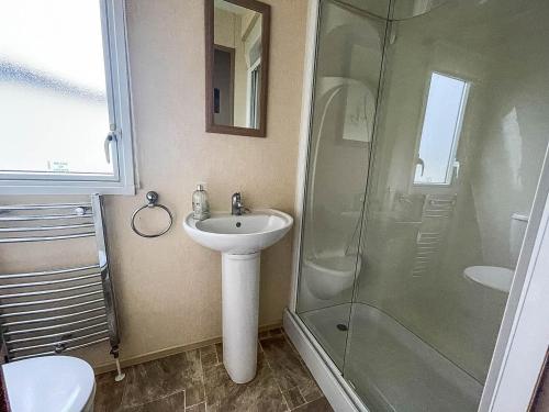 y baño con lavabo y ducha. en Lovely Caravan With Decking At Heacham Beach In Norfolk Ref 21028t, en Heacham