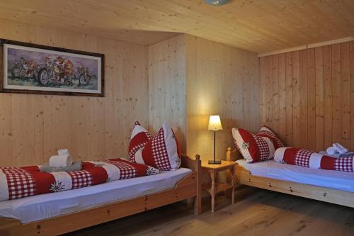 Habitación con 2 camas y almohadas rojas y blancas. en Gasthaus Bellawiese, en Sankt Antönien