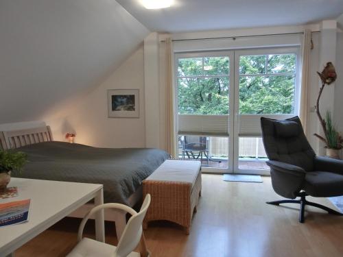 een slaapkamer met een bed, een stoel en een raam bij Ferienwohnung F6 in Graal-Müritz