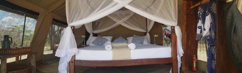 um quarto com uma cama de dossel e cortinas brancas em Makubi Safari Camp by Isyankisu em Kwa Mhinda