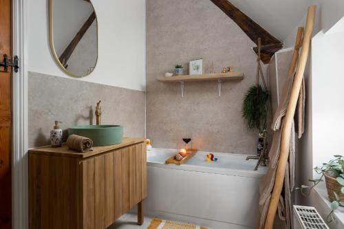 ein Badezimmer mit einer Badewanne, einem Waschbecken und einem Spiegel in der Unterkunft Stow Newly Remodeled Scandi Chic in Stow on the Wold