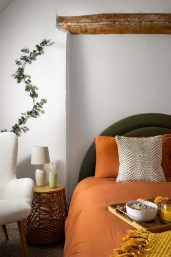 an orange bed with a tray of food on it at Stow on the Wold Scandi Chic Authentic Cottage in Stow on the Wold