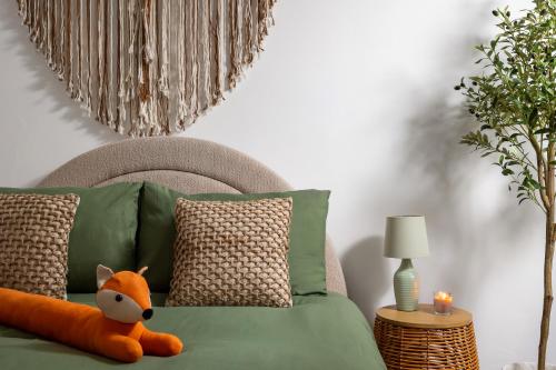 a green bed with a stuffed fox sitting on it at Stow on the Wold Scandi Chic Authentic Cottage in Stow on the Wold