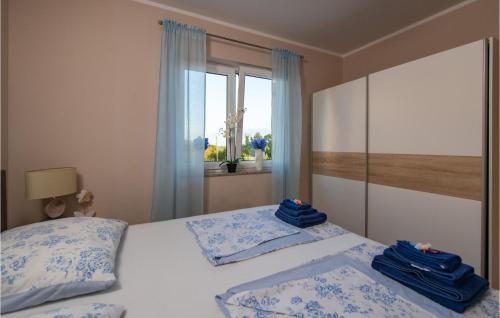 - une chambre avec 2 lits dotés d'oreillers bleus et d'une fenêtre dans l'établissement Beautiful Home In Loborika With Wi-fi, à Loborika
