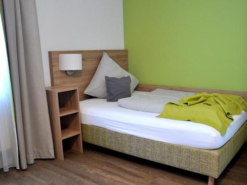 a bed in a room with a green wall at Landgasthaus zur Linde in Pleiskirchen