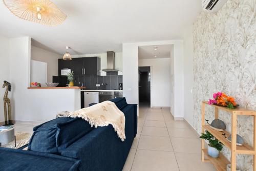 a living room with a blue couch and a kitchen at Refait à neuf, magnifique vue sur le lagon appartement 4 à 5p in Marigot