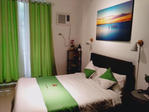 a bedroom with a large bed with green curtains at Jenny N Rose Travellers Inn in Manila