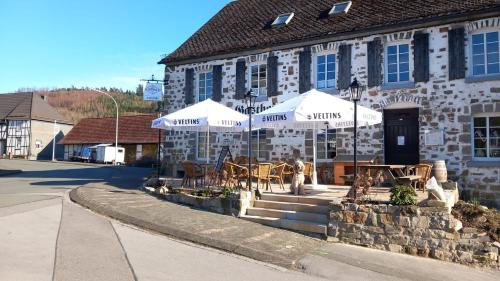 a building with tables and umbrellas in front of it at Gasthof Feische in Hellefeld