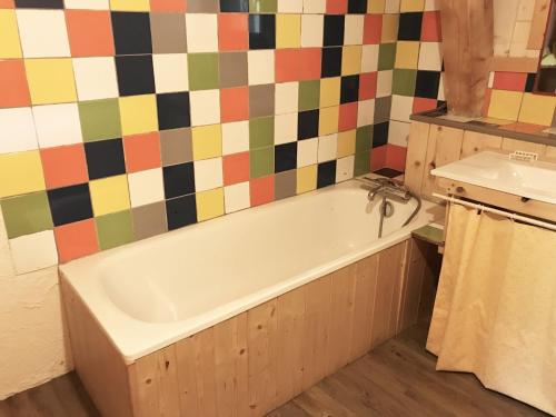 a bathroom with a tub and a colorful tiled wall at Grande demeure familiale in Les Déserts