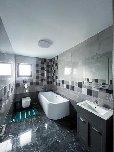 a bathroom with a tub and a toilet and a sink at Casa Maya in Curtea de Argeş