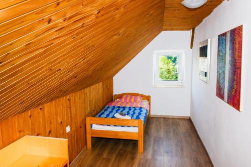 a small bed in a room with a wooden ceiling at LAAS ART GALLERY in Stari Trg pri Ložu