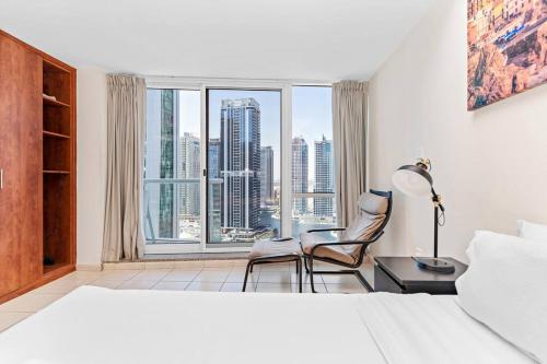 - une chambre avec un lit, deux chaises et une grande fenêtre dans l'établissement StoneTree - Studio with Amazing View in JLT, à Dubaï