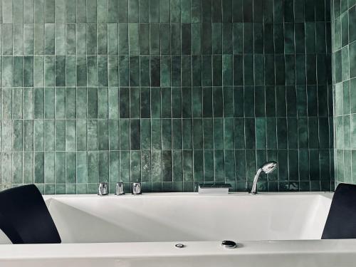 a bath tub in a bathroom with green tiles at Spar Hotel Gårda in Gothenburg