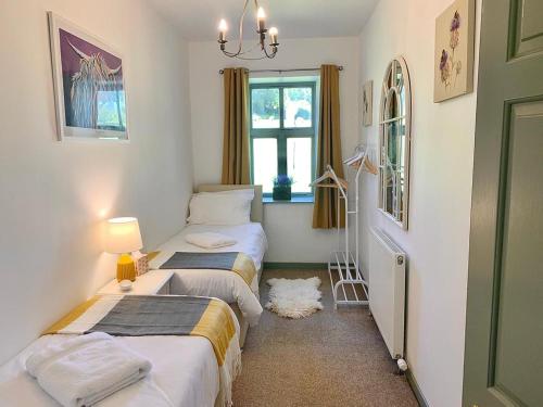 a bedroom with two beds and a window at The Stables in Meikle Wartle