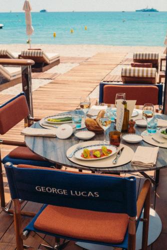 a table with a plate of food on the beach at Hôtel Martinez, in The Unbound Collection by Hyatt in Cannes
