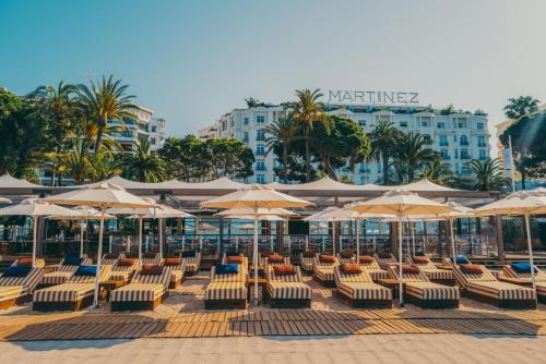 a group of chairs and umbrellas on a beach at Hôtel Martinez, in The Unbound Collection by Hyatt in Cannes