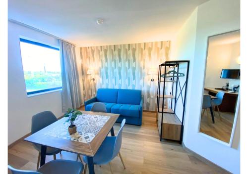 un salon avec une table et un canapé bleu dans l'établissement AU 237'- Résidence Aquatis - Futuroscope - La Conciergerie., à Chasseneuil-du-Poitou