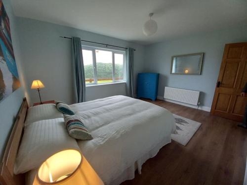 una camera da letto con un grande letto bianco e una finestra di Babeann's at Kilmeen Wood Farm, West Cork a Clonakilty