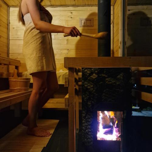 a woman is standing in front of a stove at NOVAK CHALET domki z balią Krynica Zdrój in Krynica Zdrój
