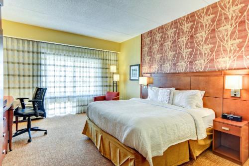 a hotel room with a bed and a desk and a chair at Courtyard by Marriott Bridgeport Clarksburg in Bridgeport