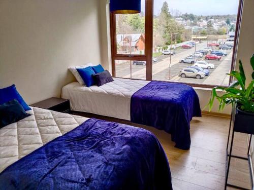 two beds in a room with a view of a street at Departamento frente al lago Villarrica in Villarrica