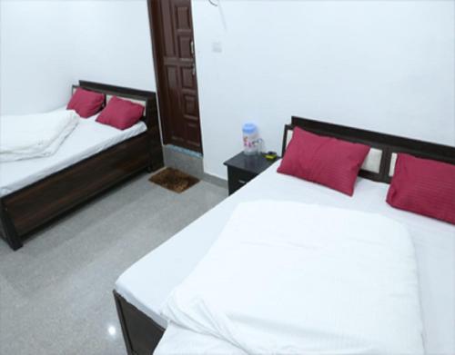a bedroom with two beds with red pillows at Hotel Prakash by StayApart in Barkot