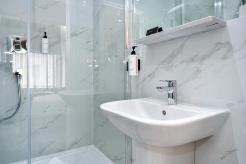 a white bathroom with a sink and a shower at Queens Park Premier London Hyde Park in London