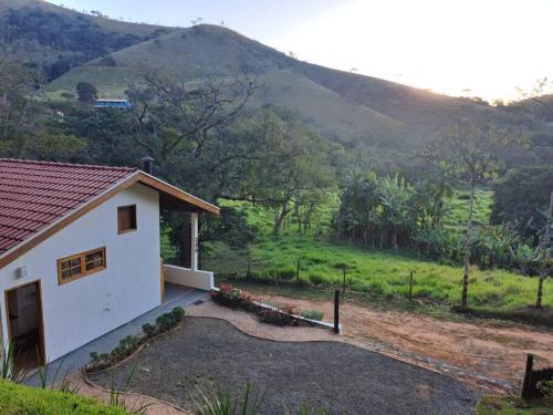 a small white house with a mountain in the background at Orobó Kaá - entre a floresta e a vida no campo in Monteiro Lobato