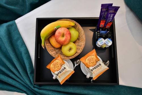 a tray with a basket of fruit and other food at Queens Park Premier London Hyde Park in London