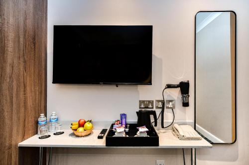 a room with a desk with a television on a wall at Queens Park Premier London Hyde Park in London