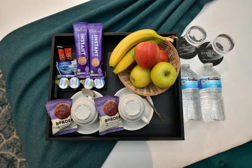 a tray of food with a basket of fruit and drinks at Queens Park Premier London Hyde Park in London