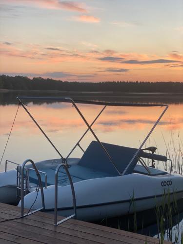 a boat is docked at a dock on a lake at Ławka i Sielawka - dom nad jeziorem z prywatnym pomostem in Tomaszkowo