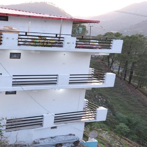 a white building with balconies on the side of it at Hotel Prakash by StayApart in Barkot