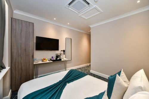 a hotel room with a bed and a flat screen tv at Queens Park Premier London Hyde Park in London