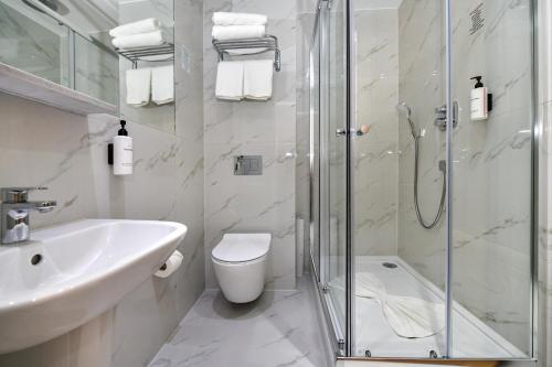 a bathroom with a shower and a toilet and a sink at Queens Park Premier London Hyde Park in London