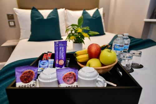 a tray of food and fruit on a bed at Queens Park Premier London Hyde Park in London