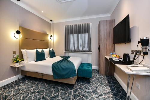 a hotel room with a bed and a desk at Queens Park Premier London Hyde Park in London