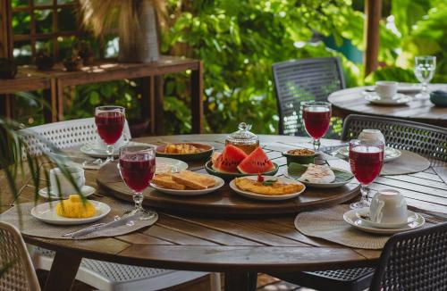 a wooden table with plates of food and glasses of wine at Pousada Moana in Fernando de Noronha