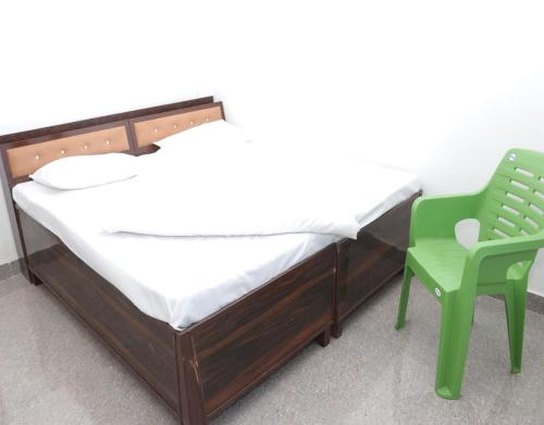 a bed and a green chair in a room at Hotel Prakash by StayApart in Barkot