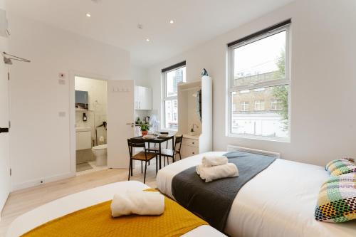 Un dormitorio con 2 camas y un escritorio en una habitación. en The Finsbury Park Star Apartments en Londres