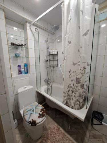 uma casa de banho com um WC e um chuveiro com uma cortina de chuveiro em Kosmos em Daugavpils